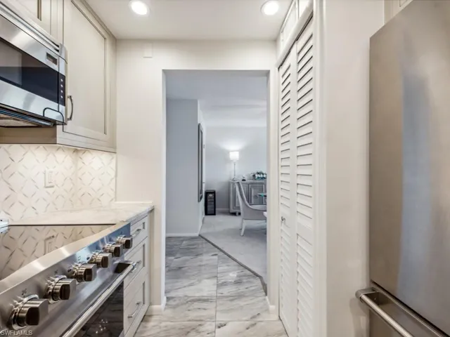 Kitchen featuring light stone counters, appliances with stainless steel finishes, and decorative backsplash