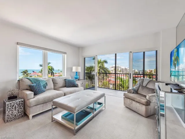 Living room with light carpet, a water view, and plenty of natural light