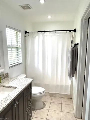 Bathroom with vanity, tile patterned floors, and shower / bathtub combination with curtain