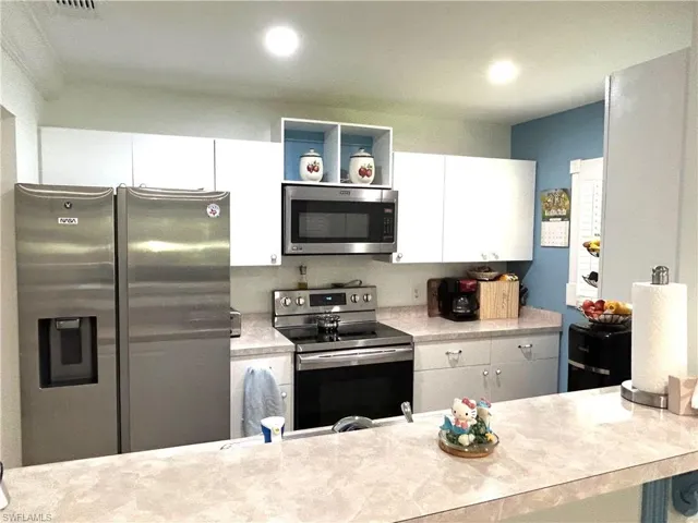 Kitchen featuring appliances with stainless steel finishes, light countertops, white cabinets, and recessed lighting