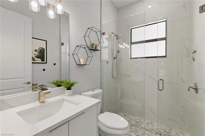 Bathroom with vanity and a marble finish shower