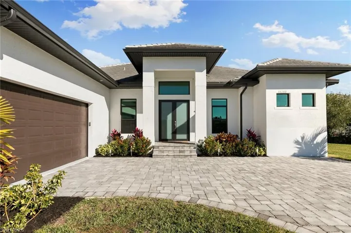 View of front of property featuring stucco siding, a tiled roof, decorative driveway, and a garage