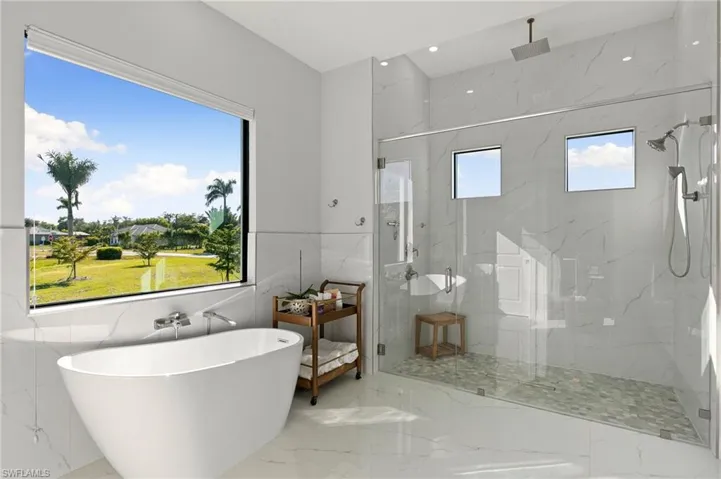 Bathroom featuring marble tiled floors, a marble finish shower, a freestanding tub, and recessed lighting