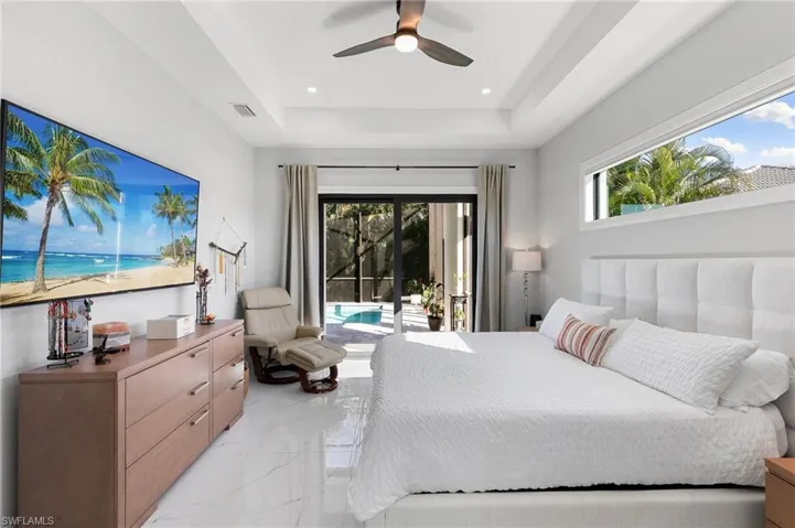 Bedroom featuring multiple windows, access to exterior, light marble finish flooring, and a ceiling fan