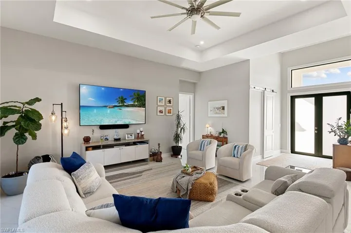 Living room featuring a tray ceiling, a barn door, french doors, a towering ceiling, and ceiling fan