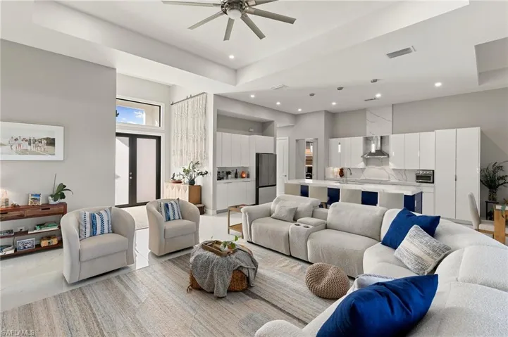 Living area featuring recessed lighting, ceiling fan, a high ceiling, and a raised ceiling