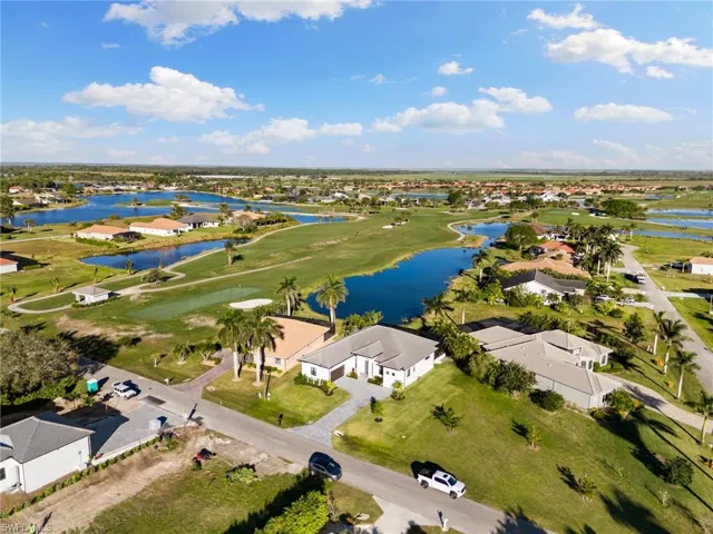 Aerial view of property's location featuring nearby suburban area, a large body of water, and a golf club