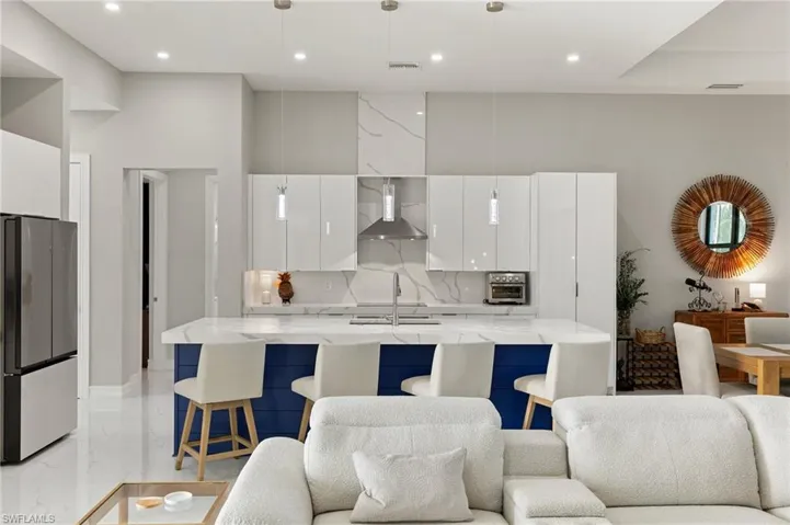 Kitchen featuring white cabinetry, blue cabinets, modern cabinets, freestanding refrigerator, and light stone countertops