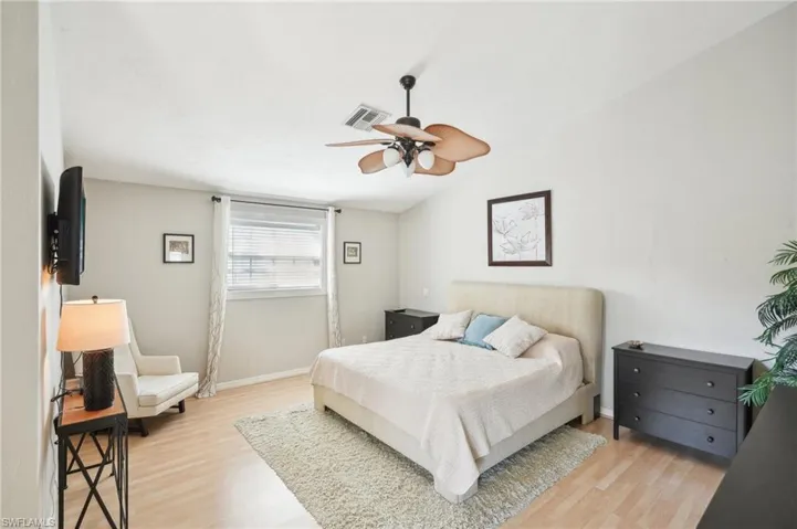 Bedroom featuring visible vents, light wood-style floors, vaulted ceiling, ceiling fan, and baseboards