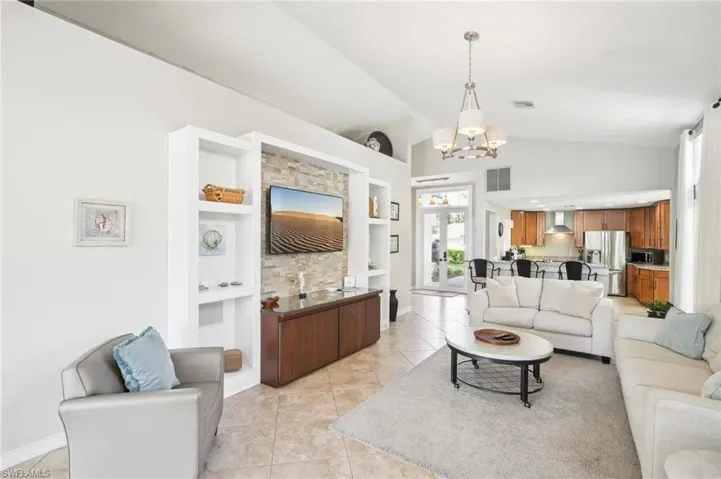 Living area featuring built in shelves, visible vents, a notable chandelier, and light tile patterned floors