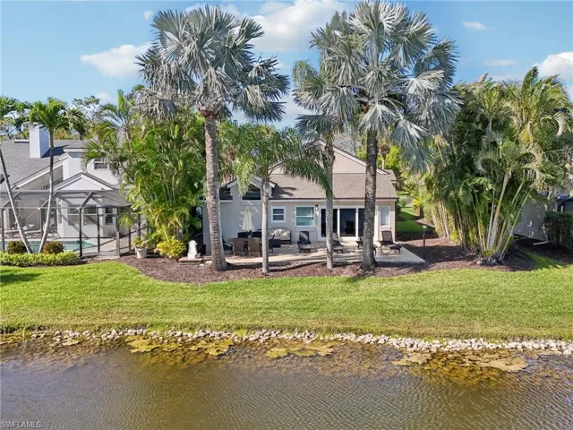 Back of property featuring a lawn, a patio area, a lanai, and a water view