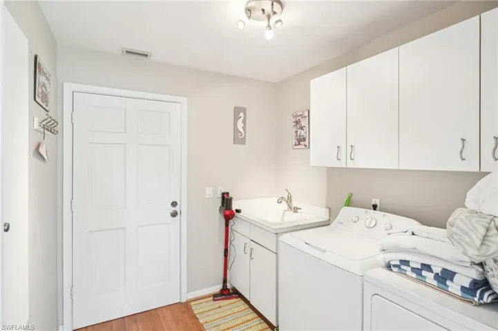 Laundry room with a sink, visible vents, washer and dryer, light wood-type flooring, and cabinet space