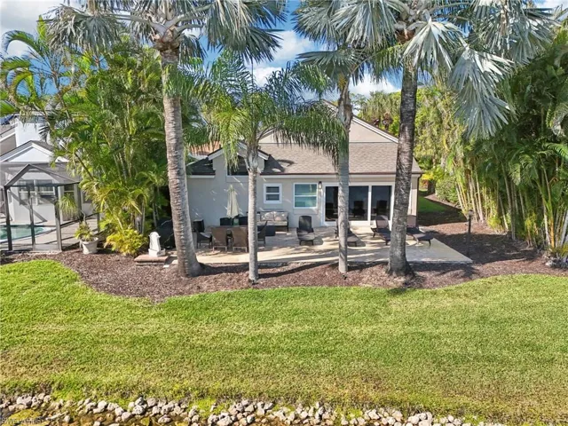 Rear view of house featuring a lanai, a patio area, a yard, and stucco siding