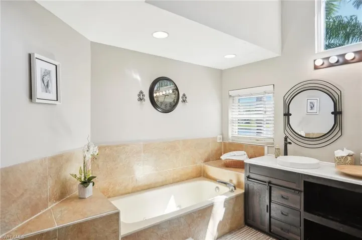 Full bath featuring a garden tub, vanity, and recessed lighting
