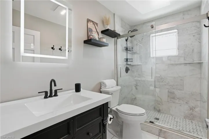 Bathroom with vanity and a marble finish shower - Virtually Edited Image