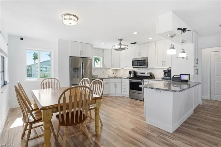Kitchen with dark stone counters, appliances with stainless steel finishes, and white cabinetry - Virtually Edited Image