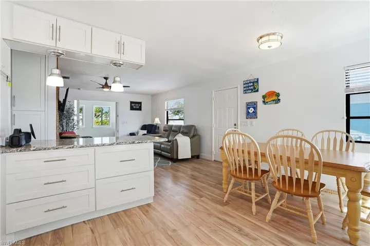 Kitchen featuring white cabinets, light stone counters, ceiling fan, and open floor plan - Virtually Edited Image