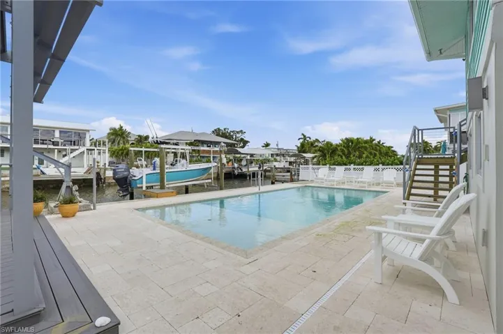 View of pool featuring boat lift, stairs, a water view, a dock, and a patio - Virtually Edited Image