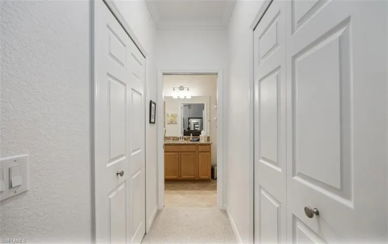 Hallway leading to primary bathroom and double closets