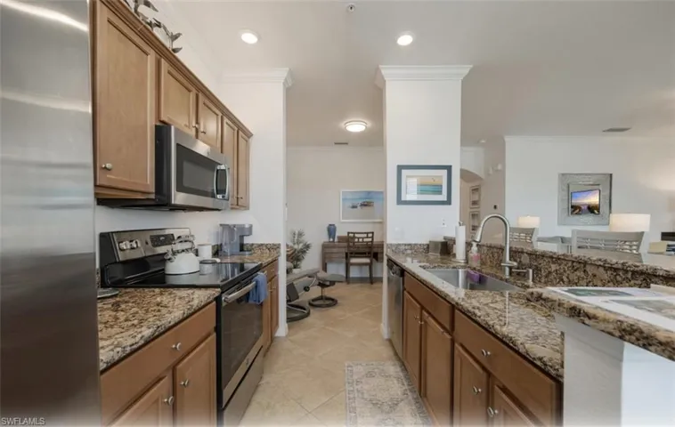 Kitchen with stainless steel appliances, brown cabinets, dark stone counters, crown molding, and recessed lighting