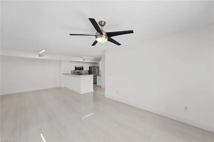 Unfurnished living room featuring a ceiling fan and a textured ceiling
