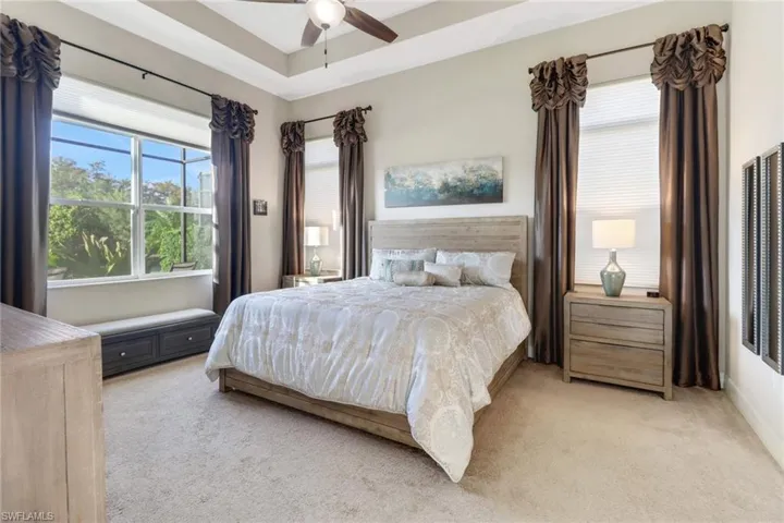 Carpeted bedroom featuring ceiling fan and multiple windows for letting natural light in.