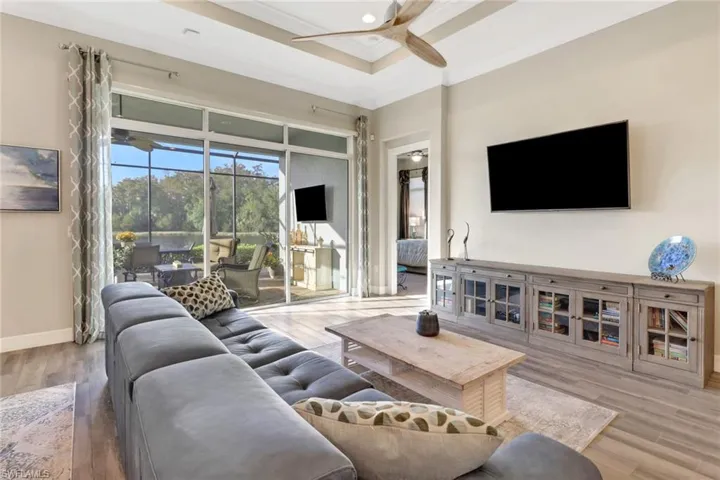 Living room has crown molding, tray ceiling and beautiful ceiling fan.
