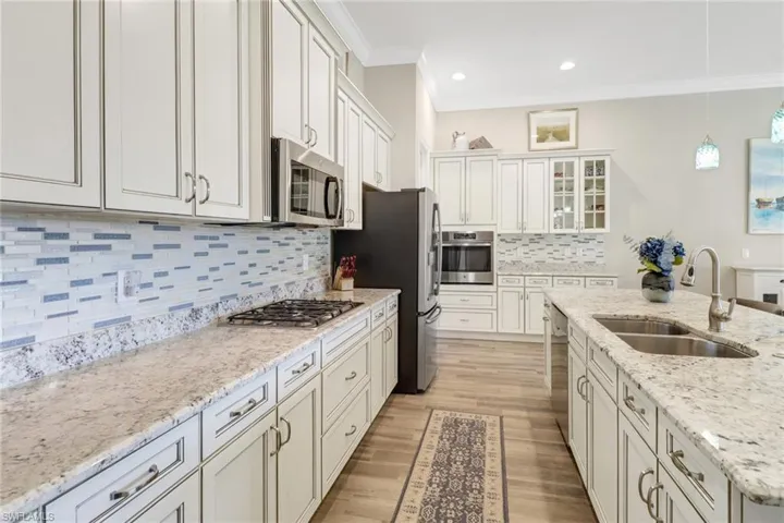 Light granite countertops and tiled backsplash.  The gas cooktop, built-in oven and stainless steel appliances give this kitchen a sleek look.
