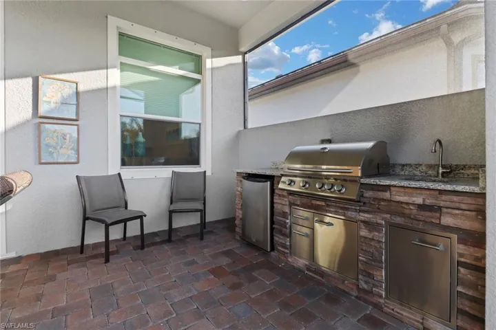 Built-in outdoor kitchen includes grill, refrigerator and sink.
