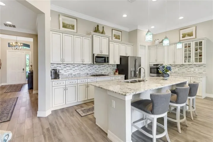 The bright kitchen has white cabinetry, a large island, and granite countertops.