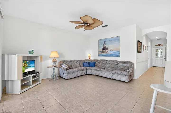 Living room with arched walkways, ceiling fan, and light tile patterned flooring