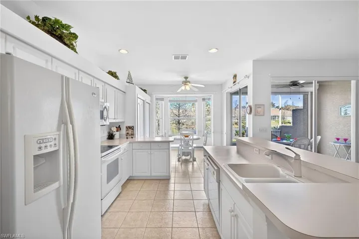 Kitchen featuring white appliances, white cabinetry, light countertops, recessed lighting, and a peninsula