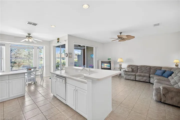 Kitchen featuring open floor plan, light countertops, ceiling fan, white dishwasher, and white cabinetry