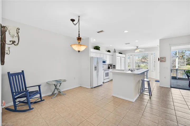 Kitchen featuring a breakfast bar, white cabinetry, a kitchen island, white appliances, and light countertops