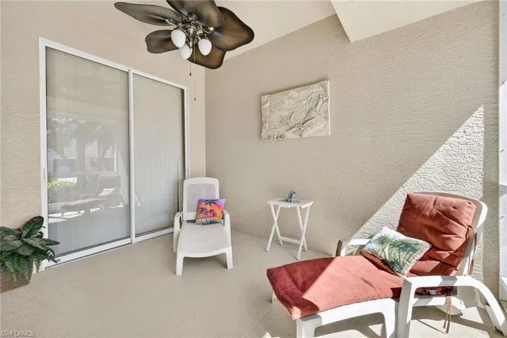 Sitting room featuring a textured wall, a ceiling fan, and carpet floors