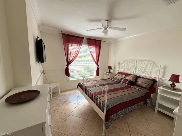 Bedroom with crown molding, light tile patterned floors, a ceiling fan, and a textured ceiling