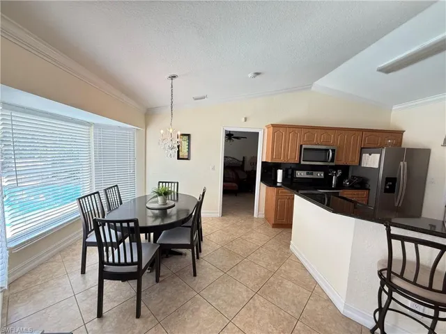 Kitchen with lofted ceiling, stainless steel appliances, a breakfast bar area, a chandelier, and pendant lighting