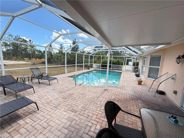 Outdoor pool featuring a patio area, a sunroom, and glass enclosure