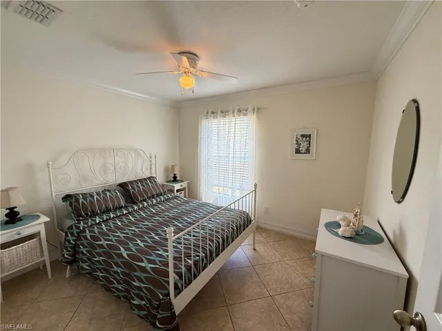 Bedroom with ornamental molding, ceiling fan, and light tile patterned floors