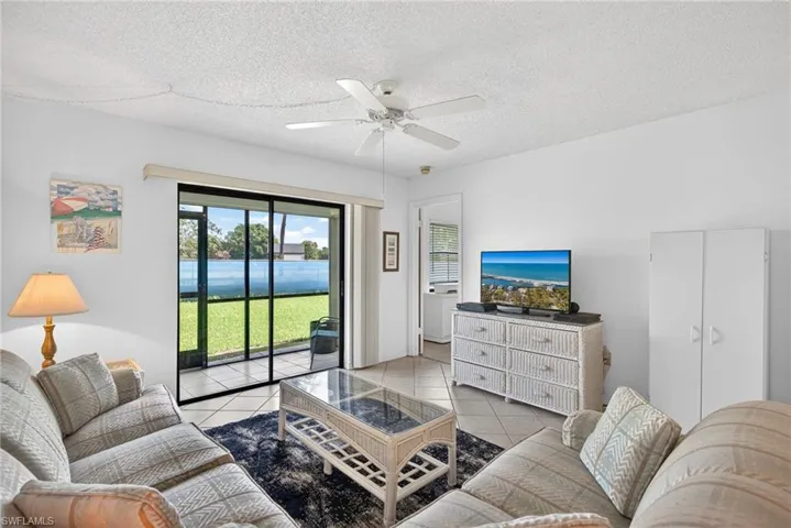 Living room featuring light tile patterned floors, a ceiling fan, and a textured ceiling