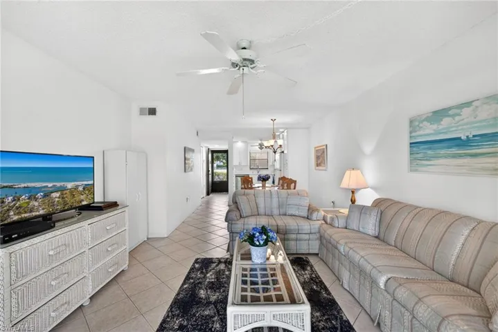 Living room featuring a ceiling fan, a textured ceiling, light tile patterned flooring, and suspended lighting