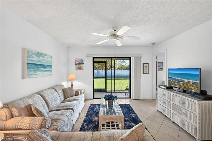 Living area with a ceiling fan, a textured ceiling, and light tile patterned floors