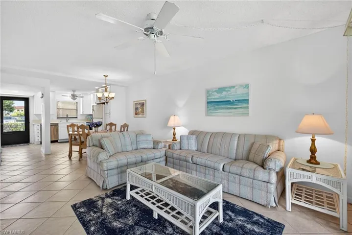 Living room with a ceiling fan, a chandelier, a textured ceiling, and light tile patterned floors