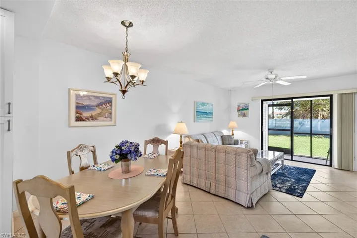 Dining space featuring a textured ceiling, a ceiling fan, light tile patterned flooring, and suspended lighting