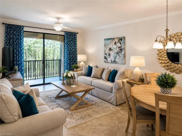 Open-concept living area with tile flooring, a built-in ceiling fan, and crown molding