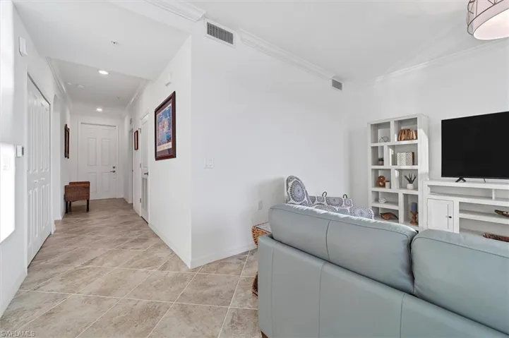 Living area featuring crown molding, light tile patterned floors, and recessed lighting