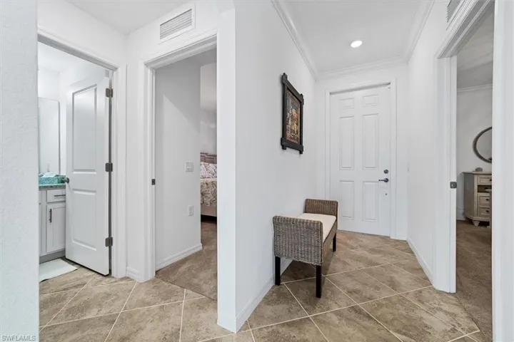 Hall with light tile patterned floors and crown molding