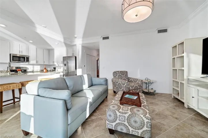Living area with crown molding, light tile patterned floors, vaulted ceiling, and recessed lighting