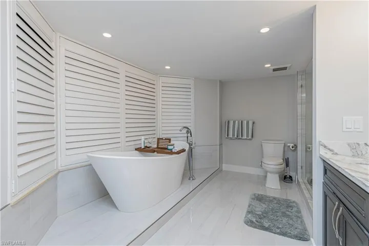 Bathroom with a tub to relax in, vanity, and toilet
