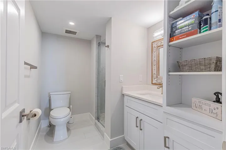 Bathroom featuring tile patterned flooring, vanity, toilet, and walk in shower
